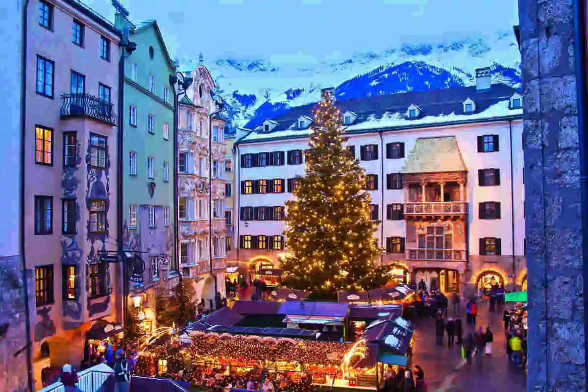 a town square of Innsbruck filled with a colourful Christmas market, photographed at dusk