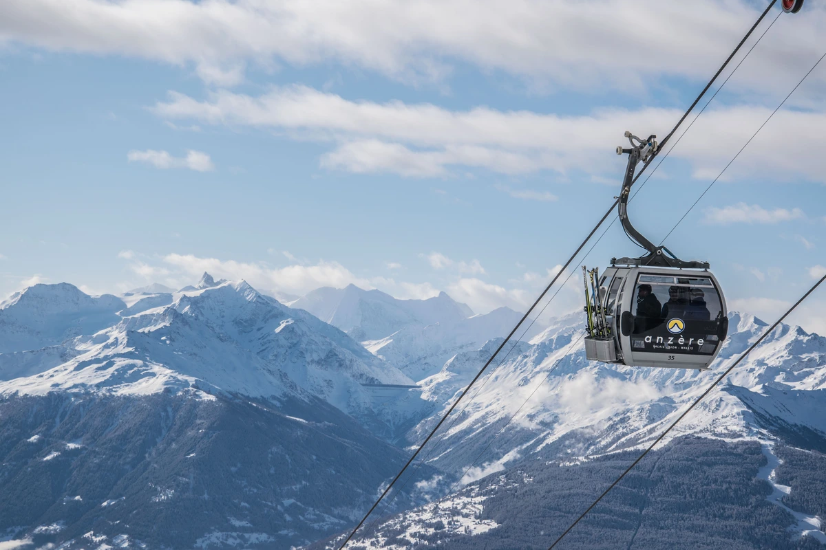 a gondola floats above snow covered mountain tops