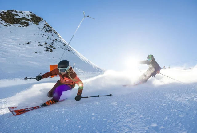 two skiers race in line down a gentle piste