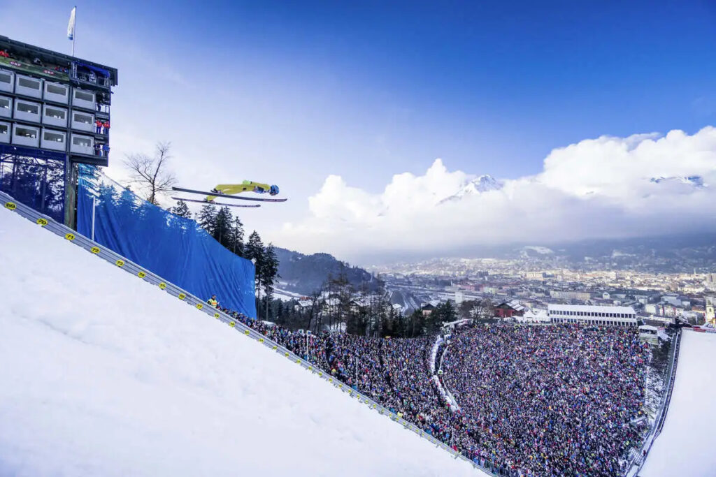 a ski jumper soars over a crowd far below